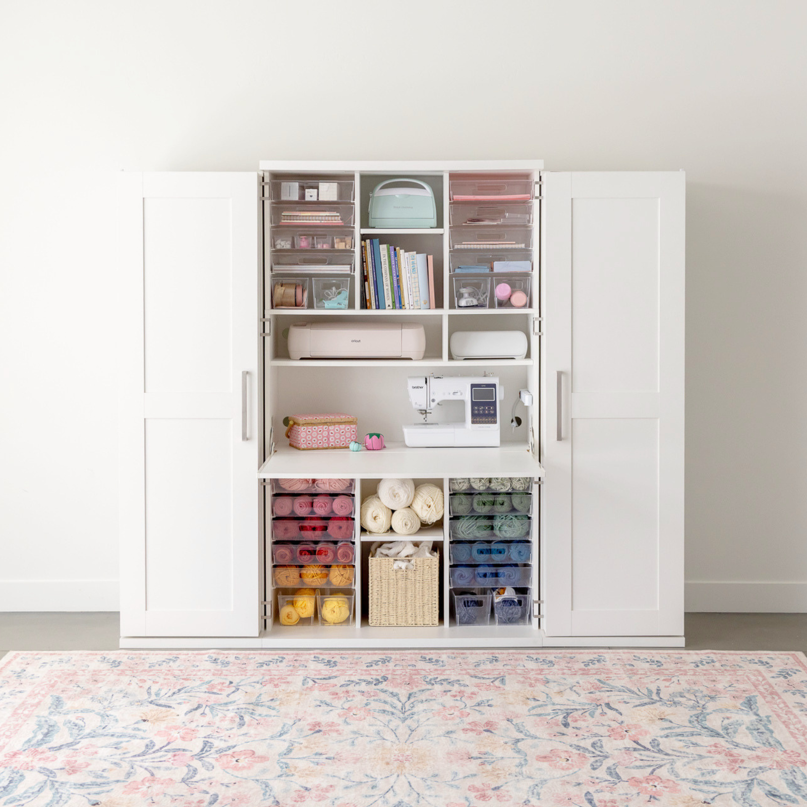 White storage cabinet with a sewing machine and yarn inside acrylic storage bins
